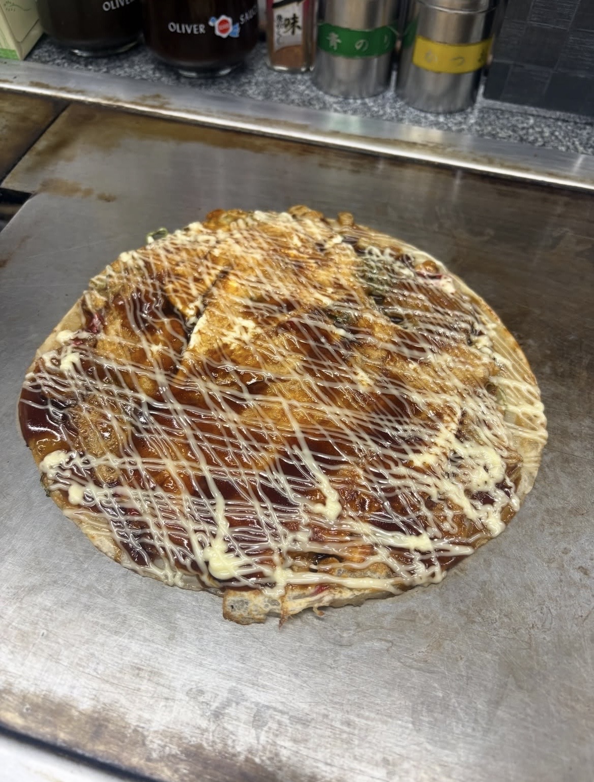 鉄板の上のうす焼き。ソースとマヨネーズが格子状にかかっている